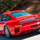 A photo of the rear quarter of a red Porsche 959 supercar.